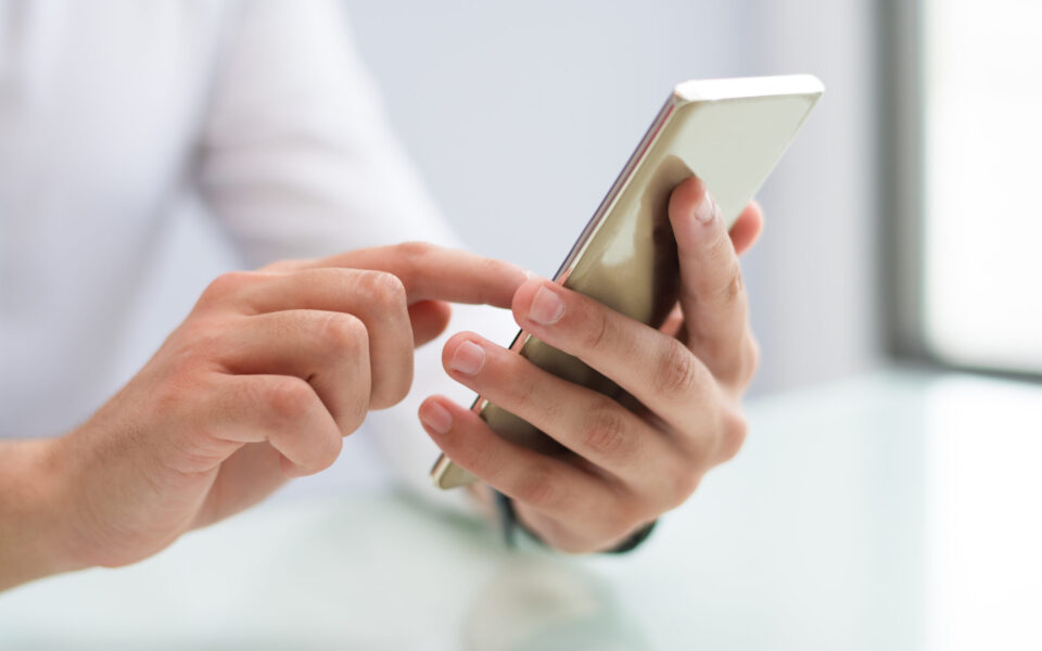Close-up of male hands using smartphone Close-up of male hands using smartphone. Unrecognizable businessman sitting at table and using mobile app. Gadget concept